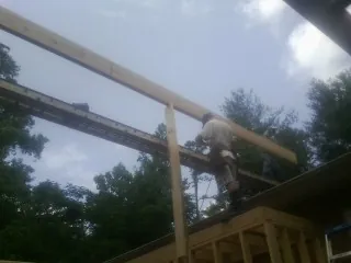 Carpenter setting a ridge beam over a new addition frame — Ice Dam Removal by Roofing Brothers in Cutchogue