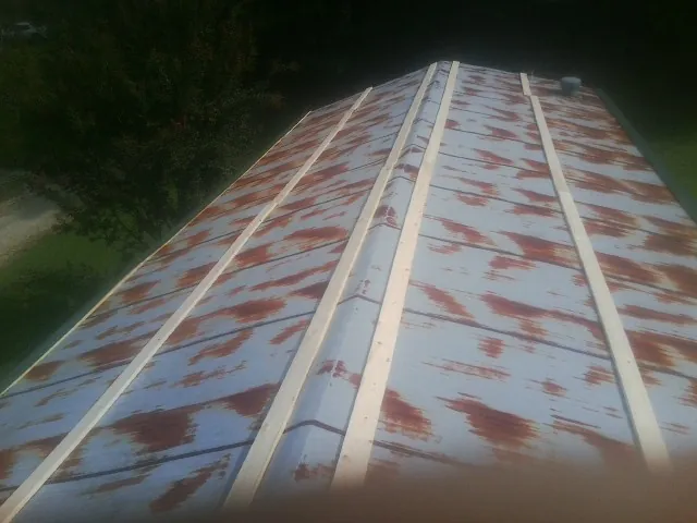 Rusted metal roof panels with new wood purlins before replacement — Storm Damage Roof Repair in Cutchogue by Roofing Brothers