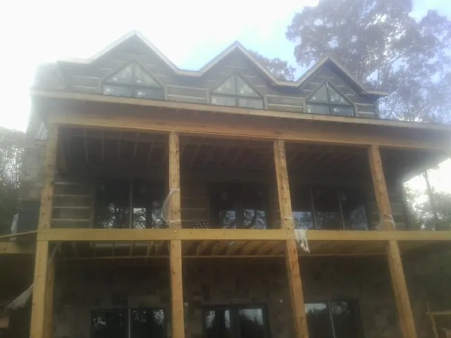 Dormers and porch framing on a large log home under construction — Roof Coating work by our crew in Cutchogue