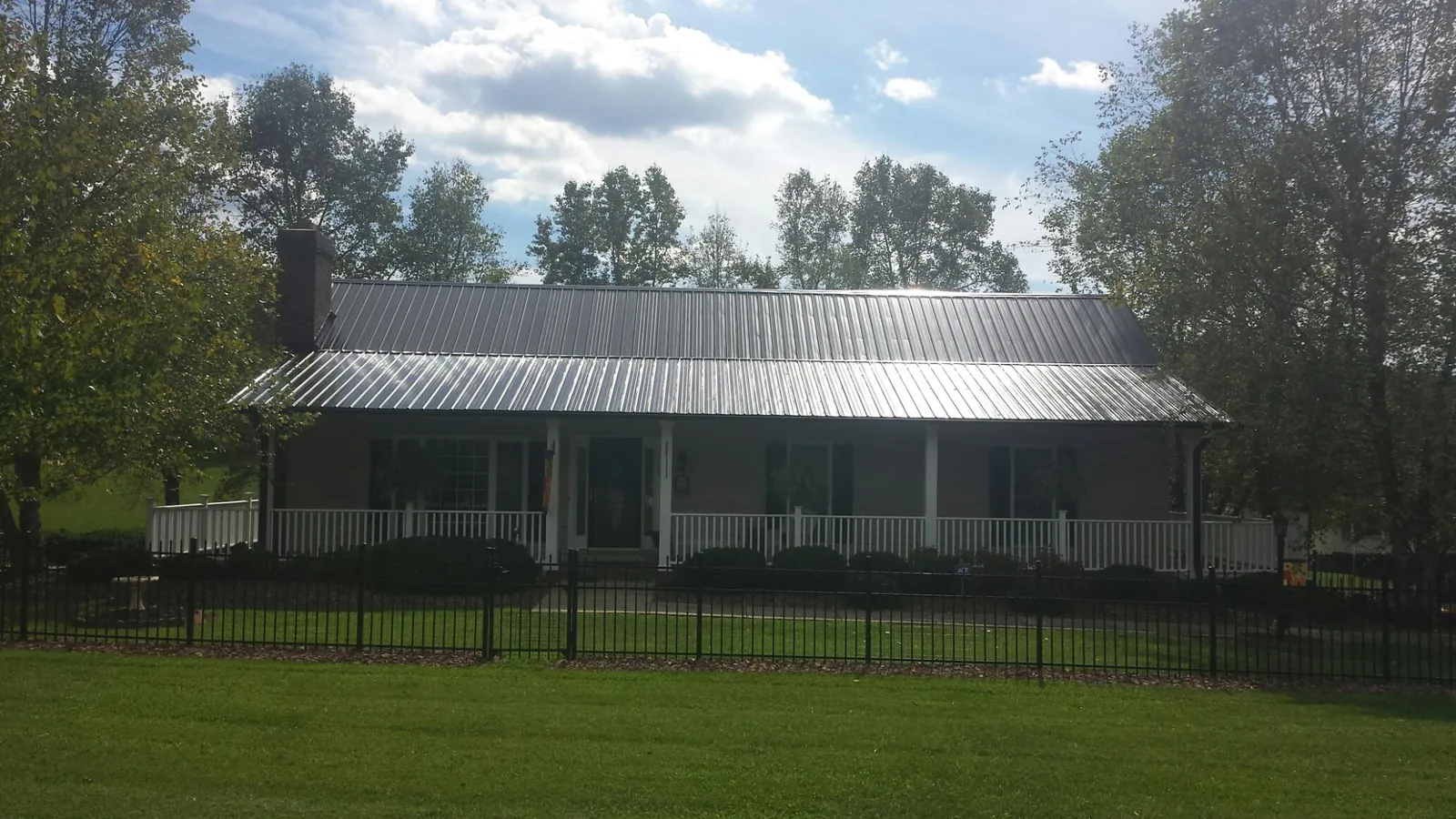 Gray metal roof on a brick ranch with a full width front porch — Gutter Guard Installation work by our crew in Cutchogue