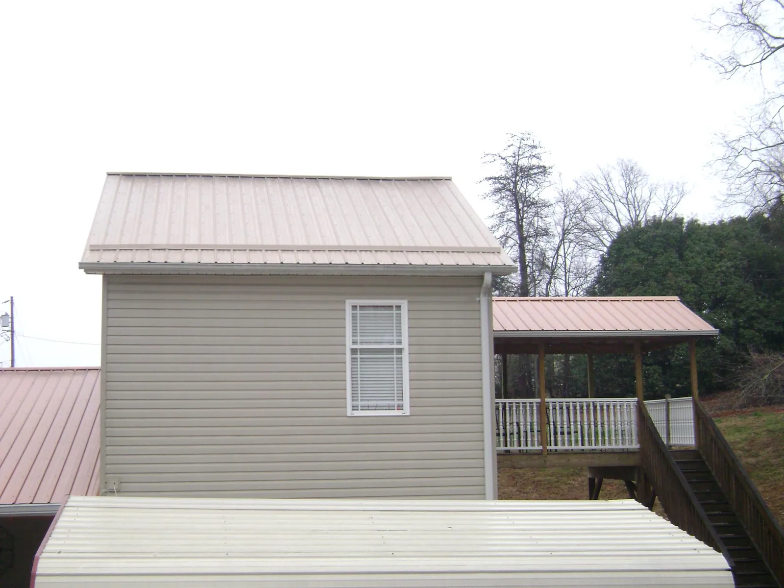 Tan metal roofs on a two story addition and attached porch, from a Roof Replacement job in Cutchogue