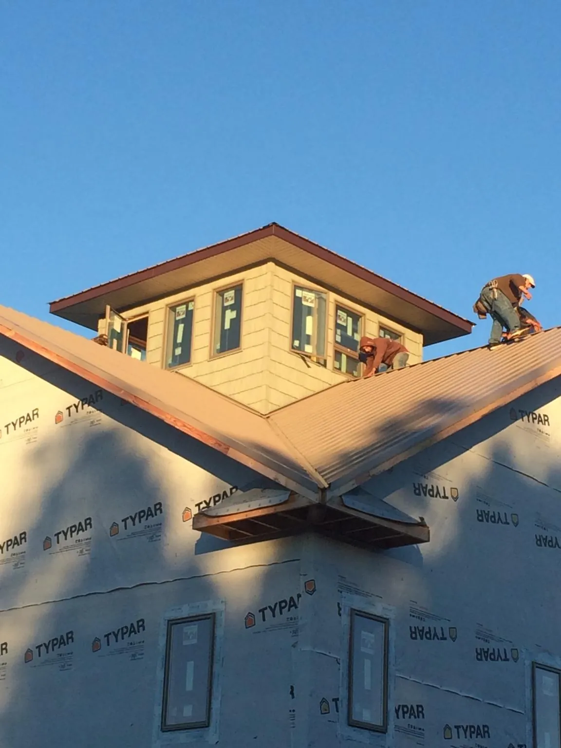 Roofers working around a rooftop cupola on a new metal roof at sunset — Roof Waterproofing in Cutchogue by Roofing Brothers